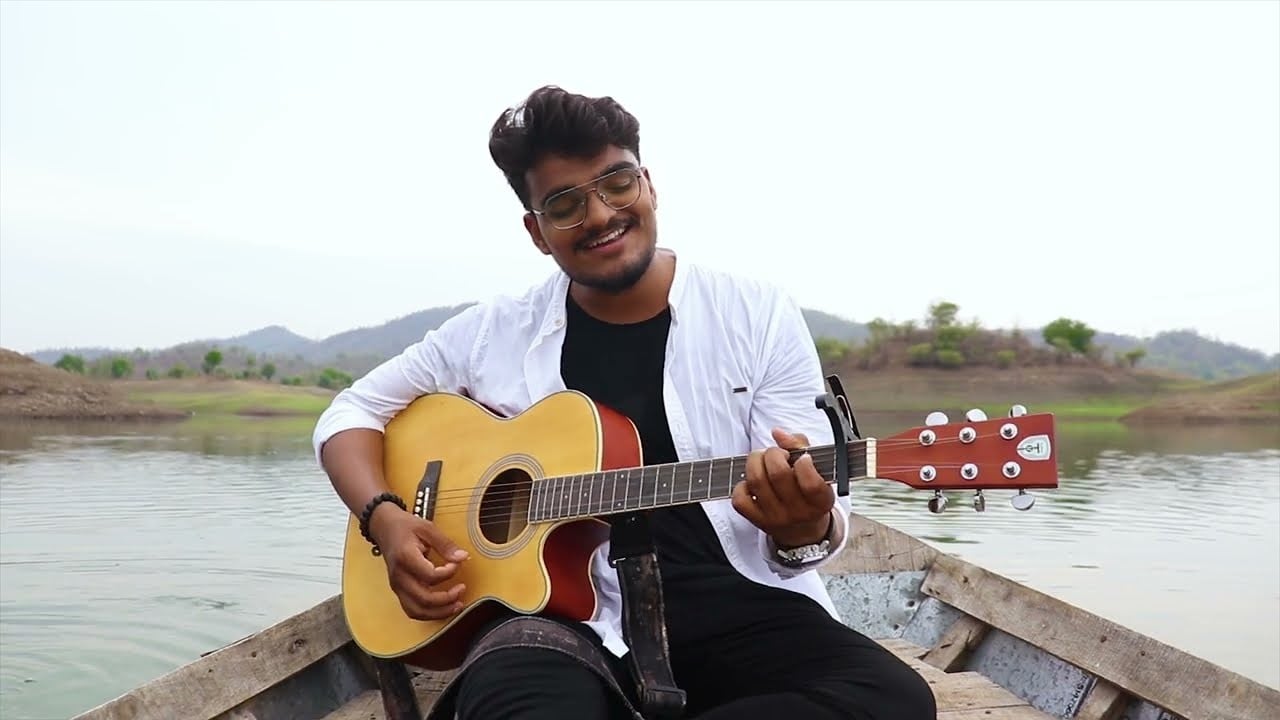 JP Kalaravkar playing an acoustic guitar in a boat on a lake, from his Kahani cover